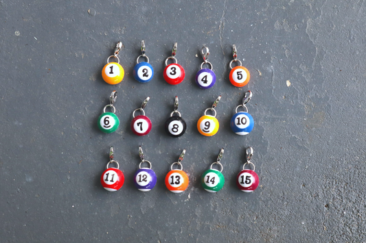 Set of billiard ball charms with numbers on a gray surface