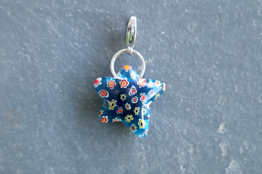 Blue star-shaped pendant with floral pattern on a gray background