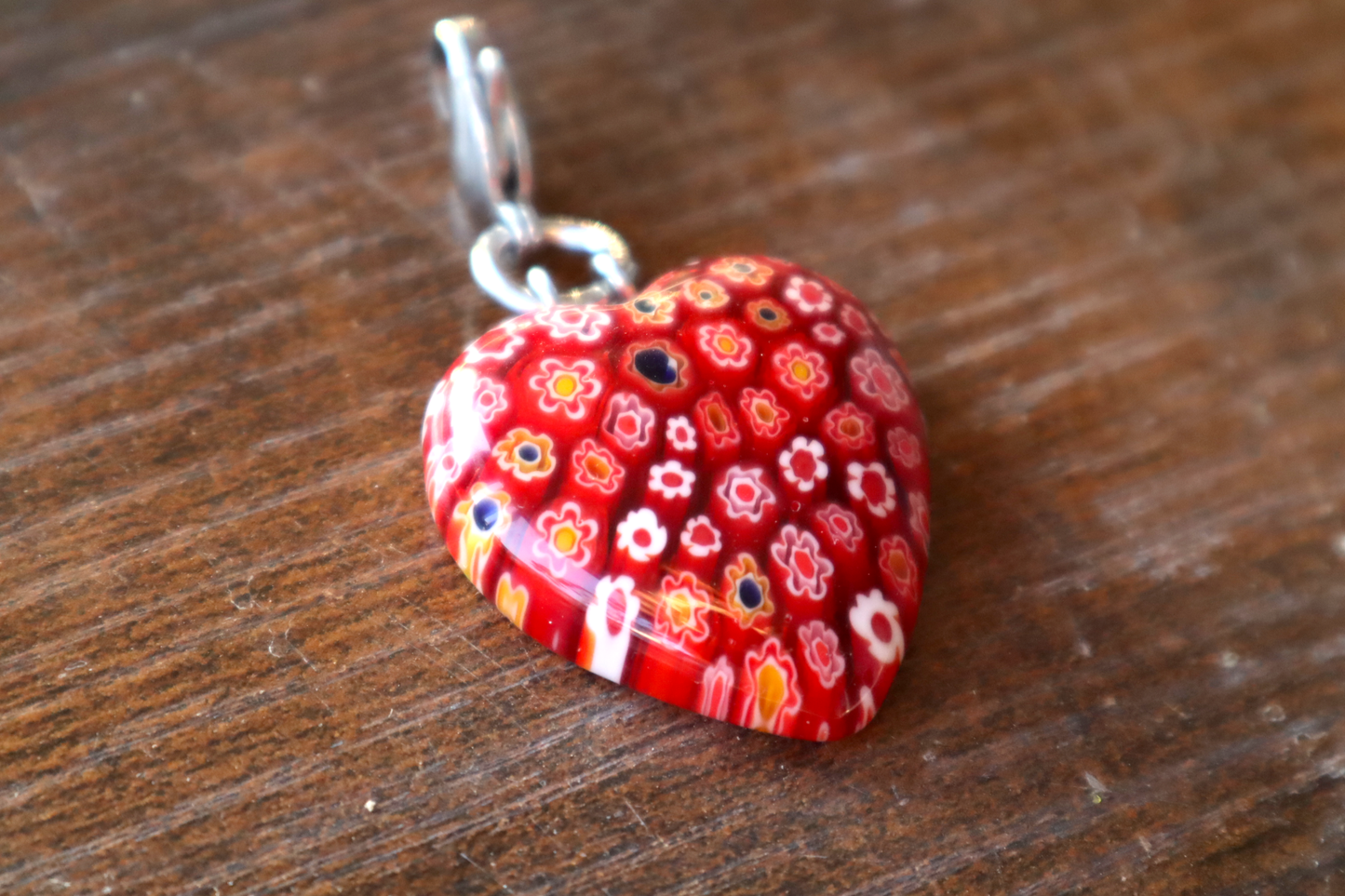Heart-shaped red floral pendant on a wooden surface