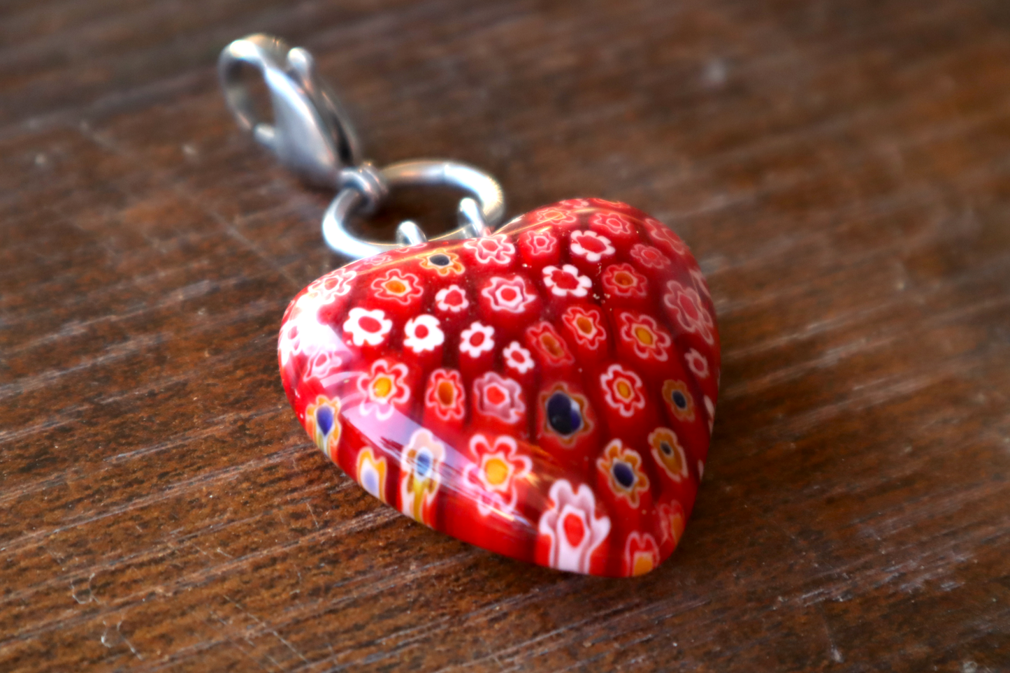 Red floral patterned heart-shaped pendant on a wooden surface