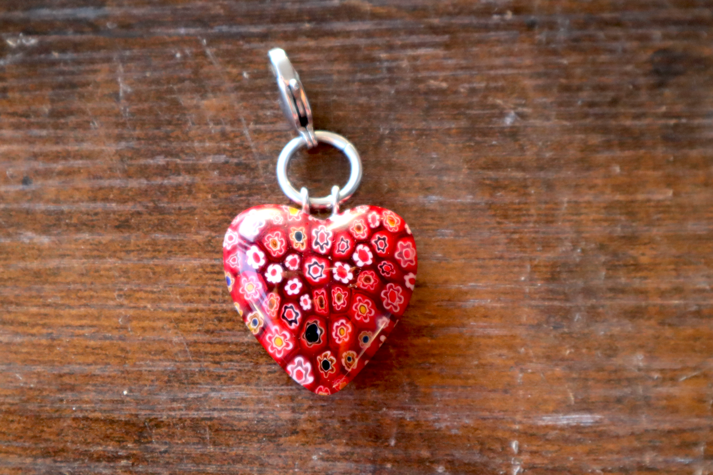 Red heart-shaped pendant with floral pattern on a wooden surface