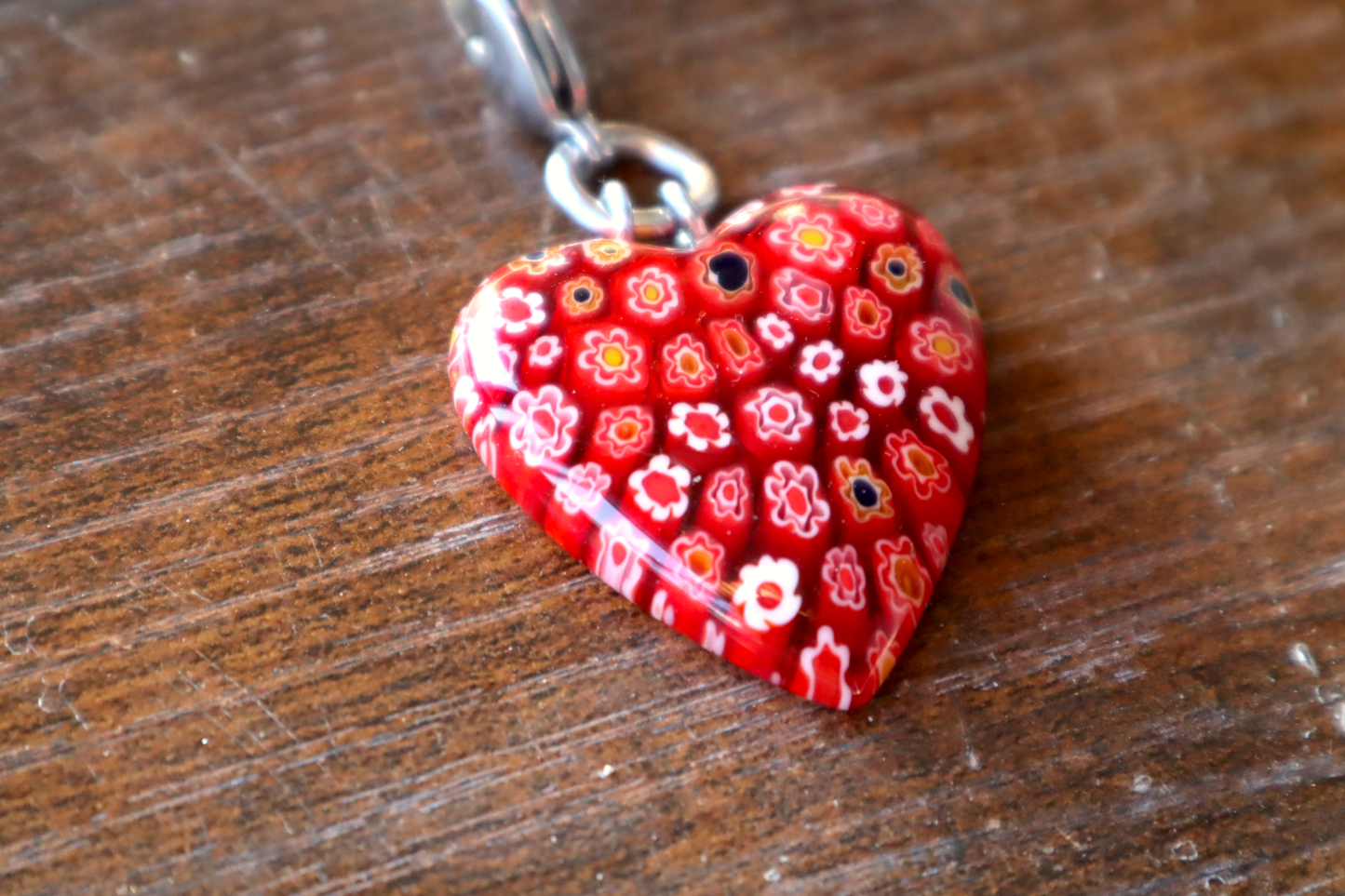 Heart-shaped red floral pendant on a wooden surface