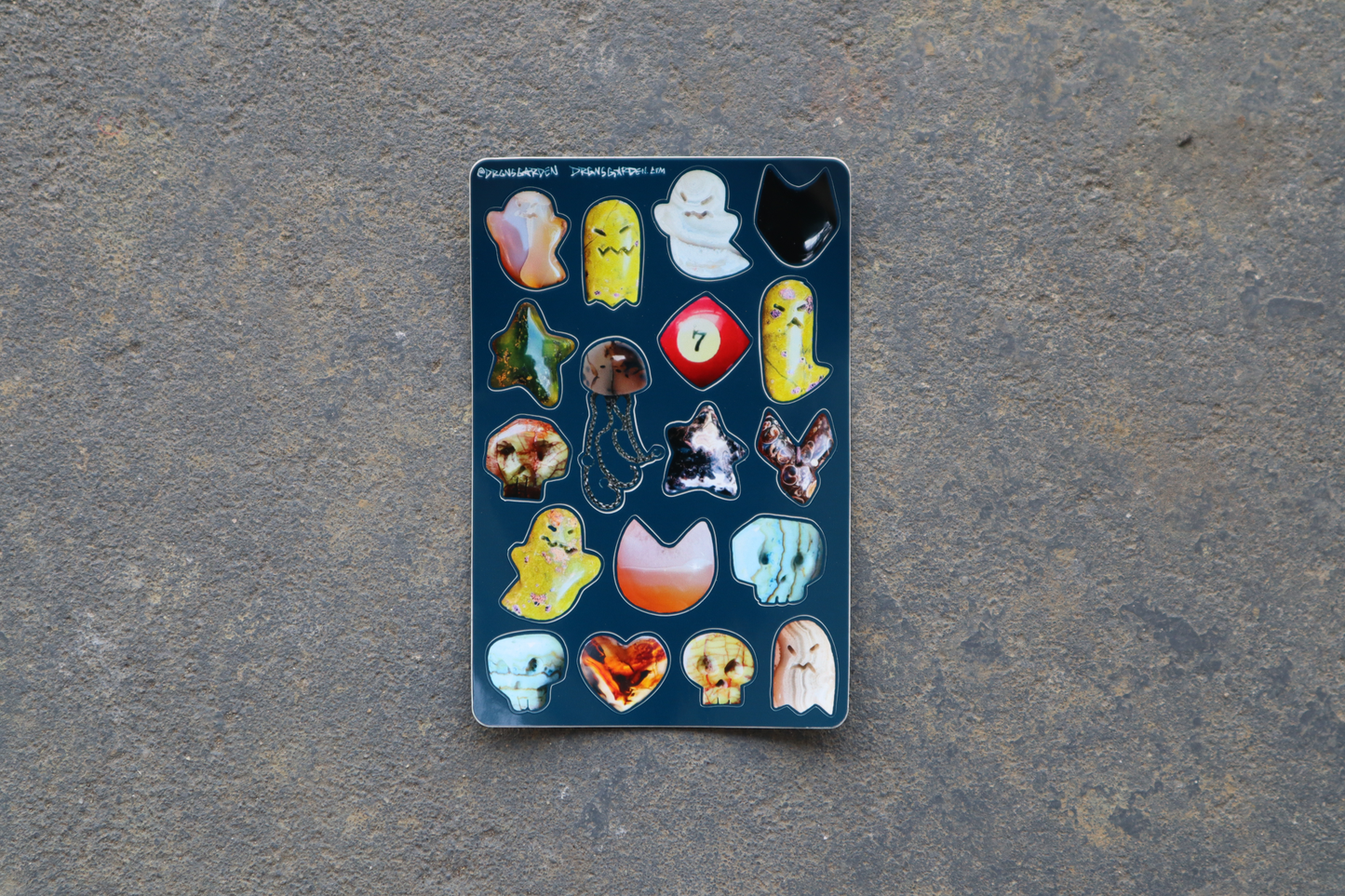 A 4" x 6" sticker sheet of 18 different stone carving photos made into stickers. Sticker sheet sits atop a gray surface