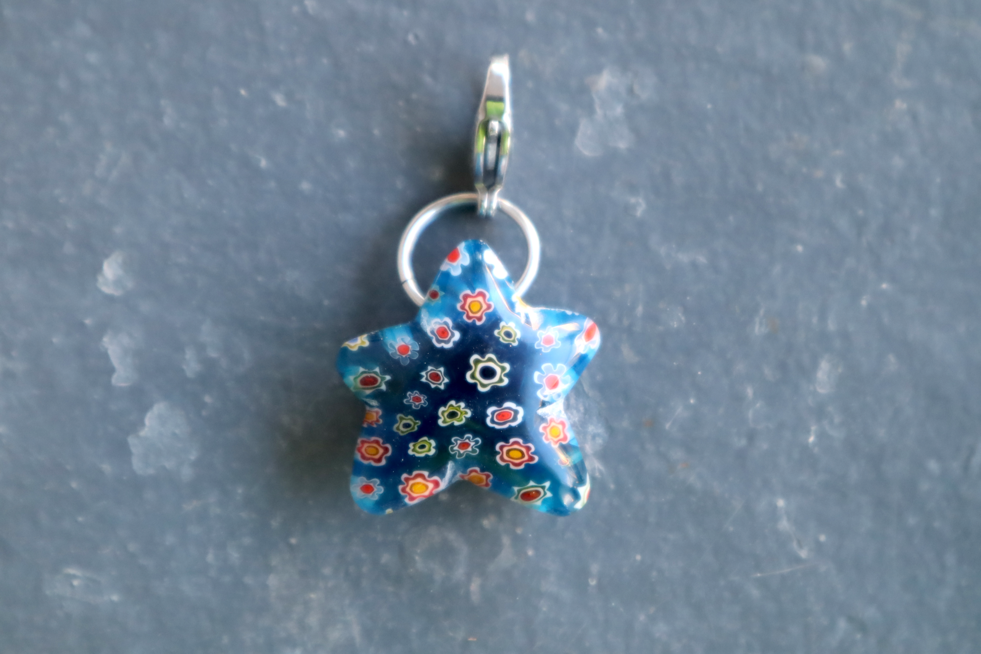 Blue star-shaped charm with floral pattern on a gray background
