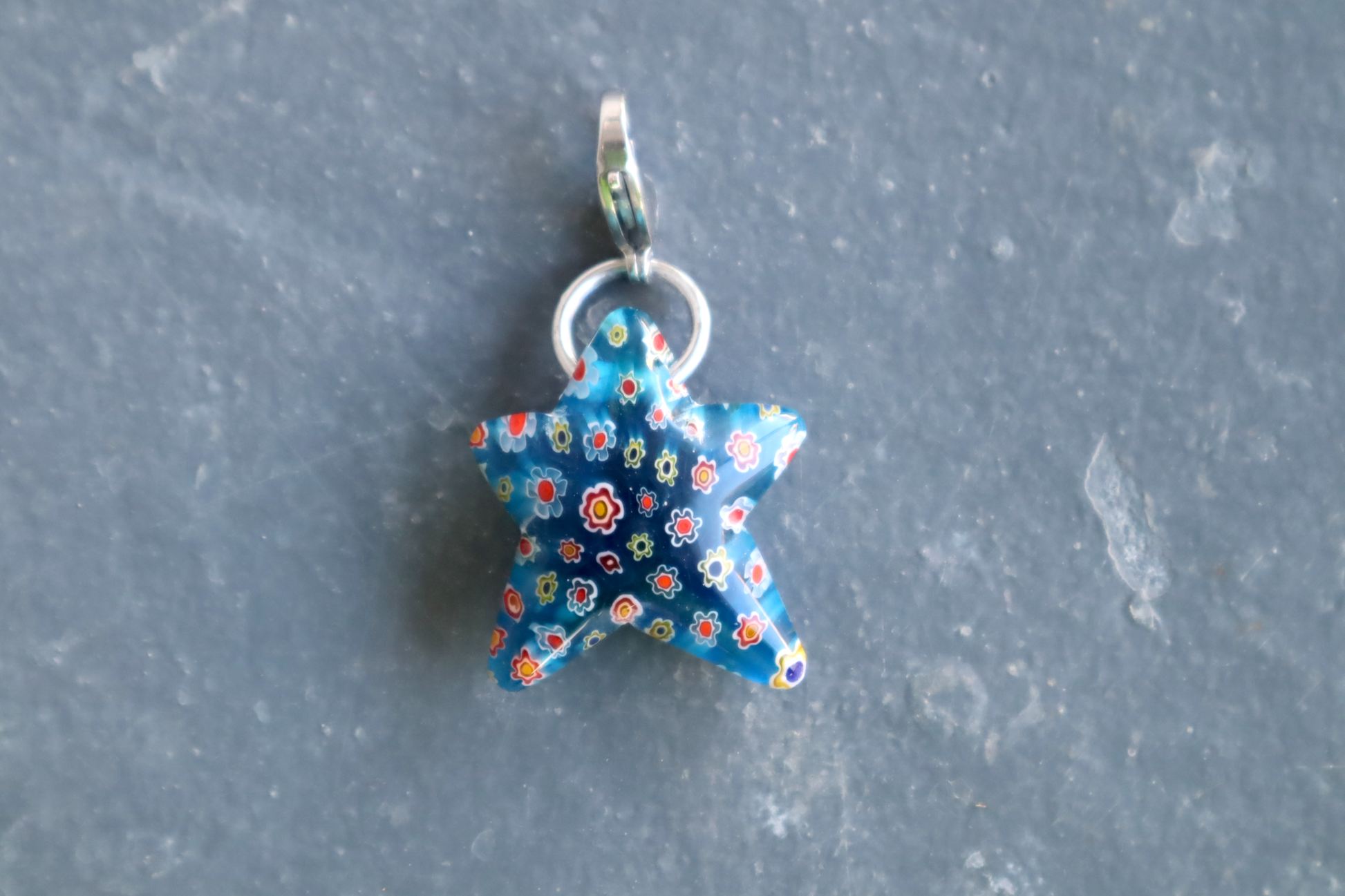 Star-shaped blue pendant with floral pattern on a gray background