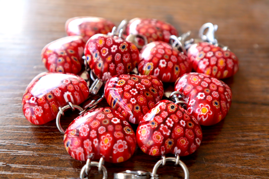 Red floral keychains on a wooden surface