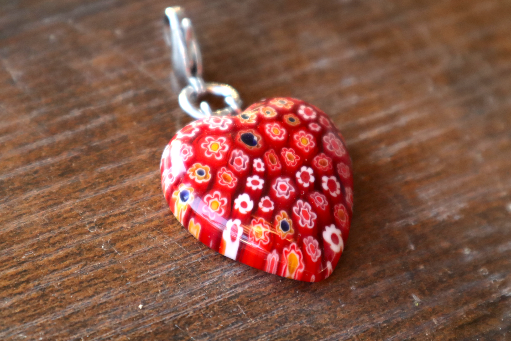 Heart-shaped red floral pendant on a wooden surface