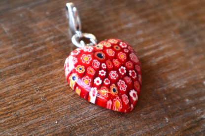 Heart-shaped red floral pendant on a wooden surface