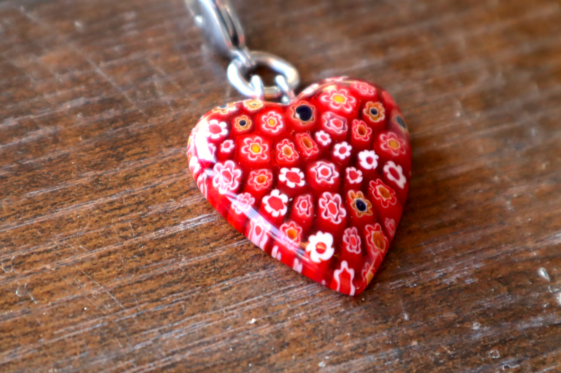 Heart-shaped red floral pendant on a wooden surface