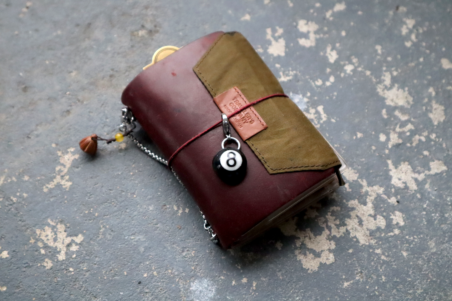 A red/brown leather wallet with a pool ball charm