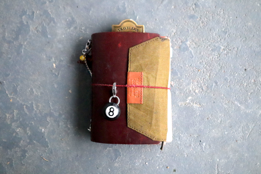 Leather-bound notebook with a keychain on a textured gray surface