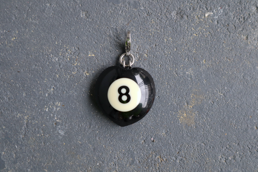 Black billiard ball pendant with number 8 on a gray surface